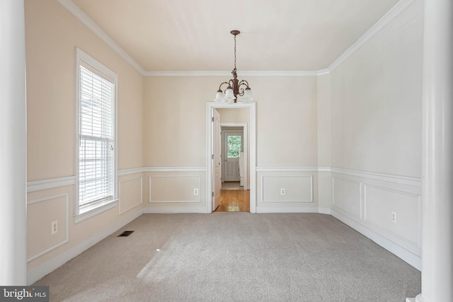 carpeted spare room featuring a chandelier and ornamental molding