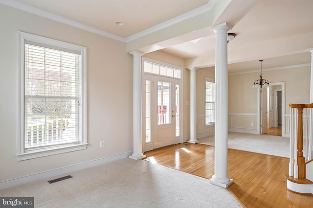 carpeted entryway featuring crown molding and decorative columns