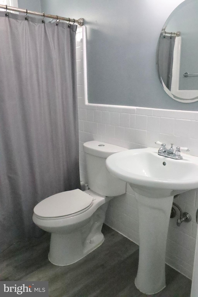 bathroom featuring hardwood / wood-style floors, toilet, curtained shower, and tile walls