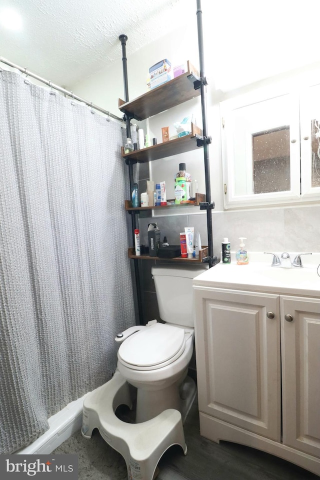 bathroom with vanity, toilet, a textured ceiling, and a shower with curtain