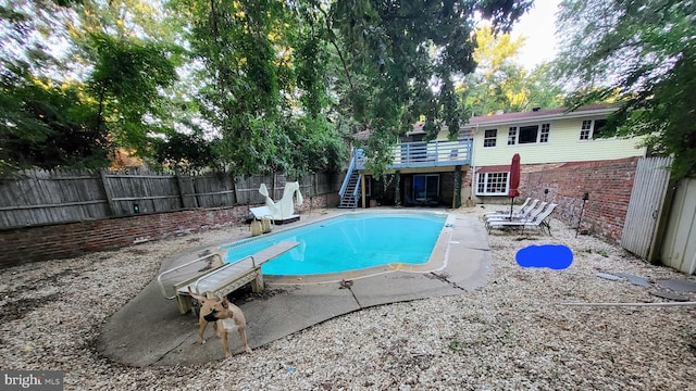 view of swimming pool with a diving board, a patio, and a wooden deck