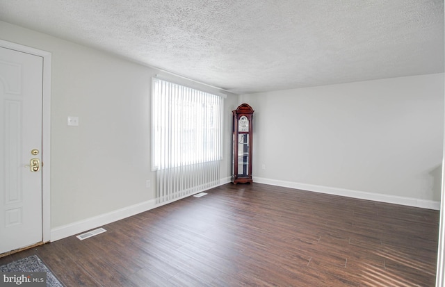 spare room with dark hardwood / wood-style flooring and a textured ceiling