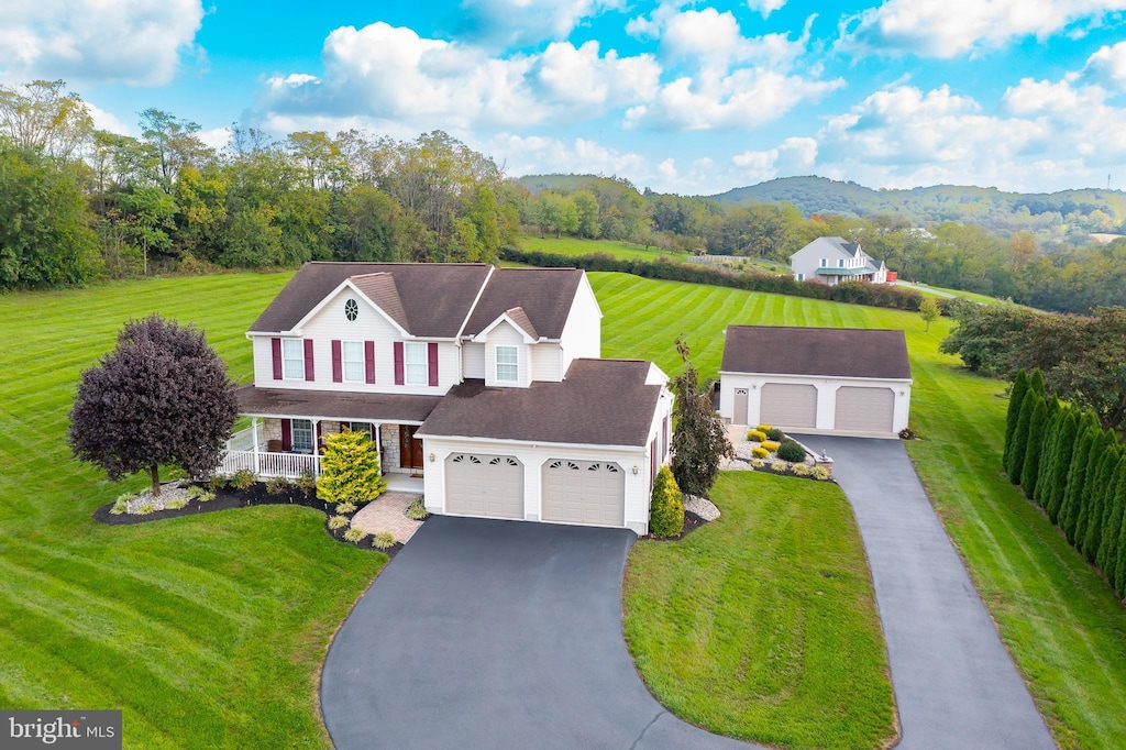 view of front facade with a front yard, a mountain view, covered porch, and a garage