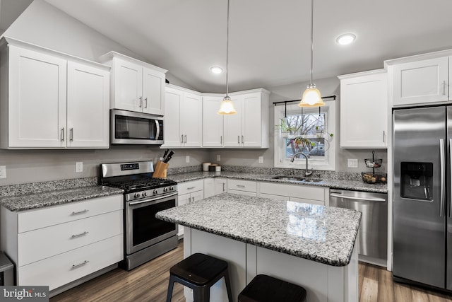 kitchen featuring sink, a kitchen island, pendant lighting, stainless steel appliances, and white cabinets