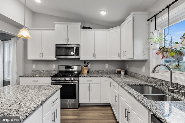 kitchen with sink, white cabinetry, decorative light fixtures, vaulted ceiling, and appliances with stainless steel finishes