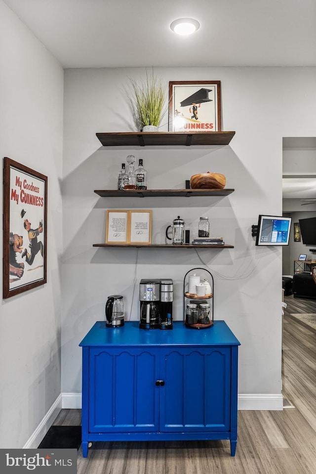 bar with hardwood / wood-style floors and blue cabinets