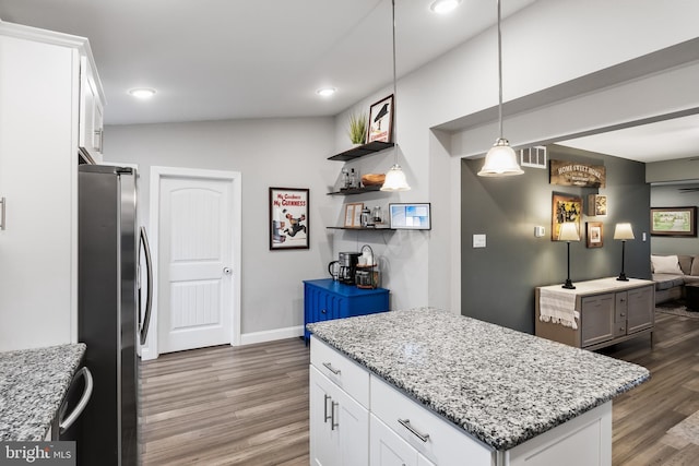 kitchen featuring stainless steel fridge, a center island, hanging light fixtures, and white cabinets