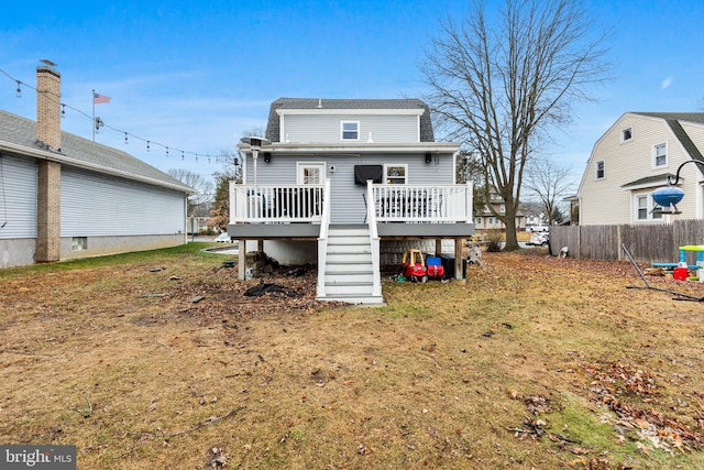 rear view of property featuring a wooden deck and a lawn