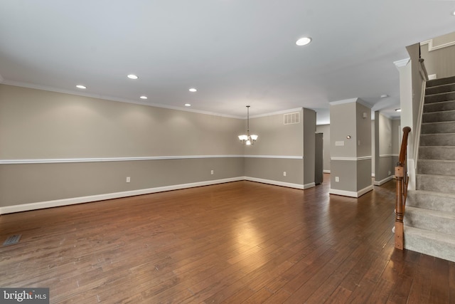 spare room with dark hardwood / wood-style floors, ornamental molding, and an inviting chandelier