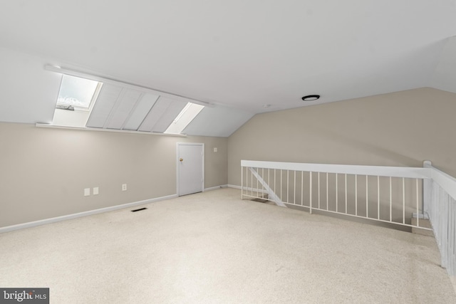 bonus room with vaulted ceiling with skylight and light carpet