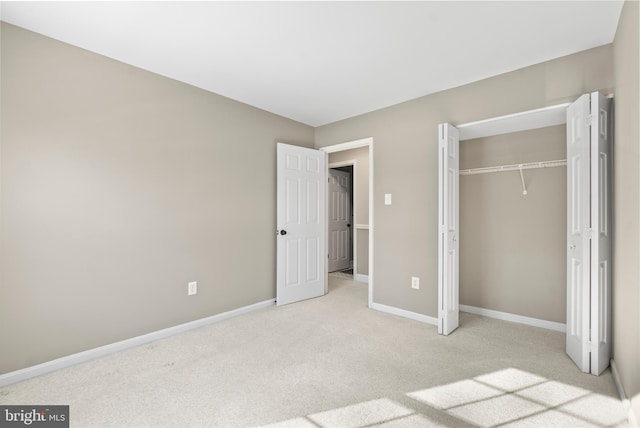 unfurnished bedroom with light colored carpet and a closet