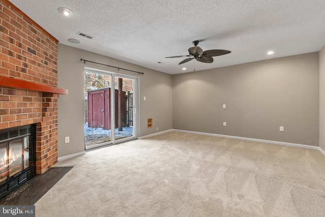 unfurnished living room featuring dark colored carpet, a textured ceiling, ceiling fan, and a fireplace