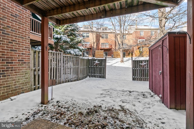 snow covered gate featuring a storage unit