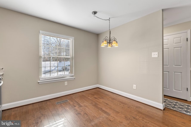 unfurnished room with a chandelier and hardwood / wood-style floors