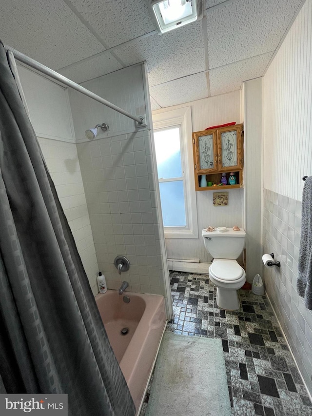 bathroom featuring toilet, shower / bathtub combination with curtain, and a drop ceiling