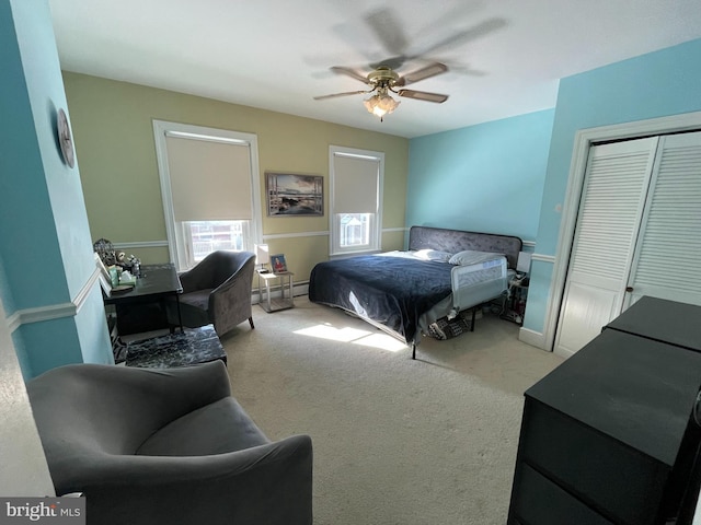 bedroom with a baseboard heating unit, ceiling fan, a closet, and carpet floors