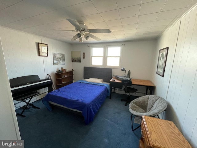 bedroom featuring ceiling fan, carpet flooring, and wood walls