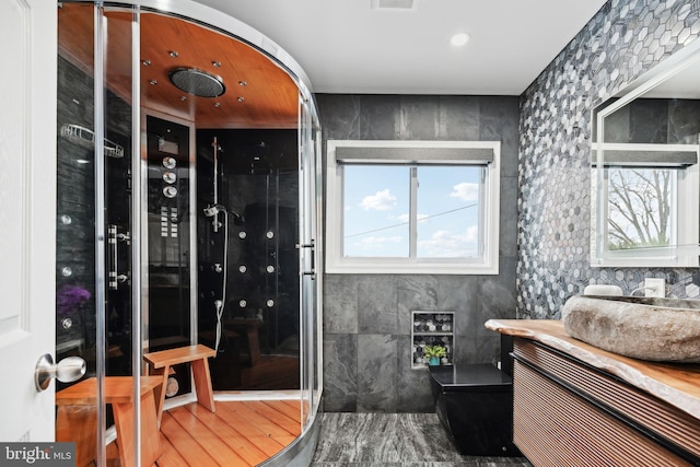 bathroom featuring wood-type flooring, tile walls, and vanity