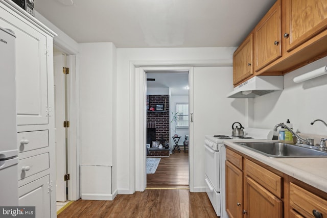 kitchen with sink, white appliances, a fireplace, and wood-type flooring