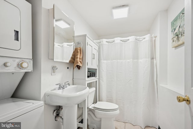 bathroom featuring sink, stacked washer / drying machine, and toilet