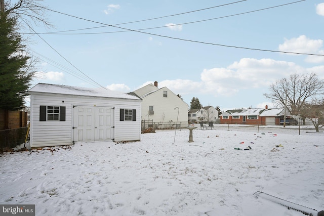 snow covered back of property with a shed