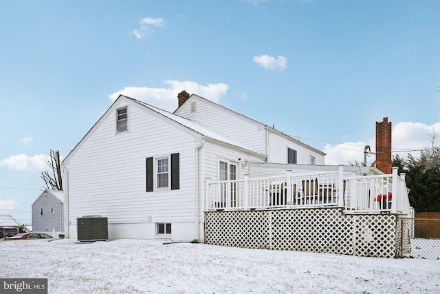 snow covered house with a deck and central AC