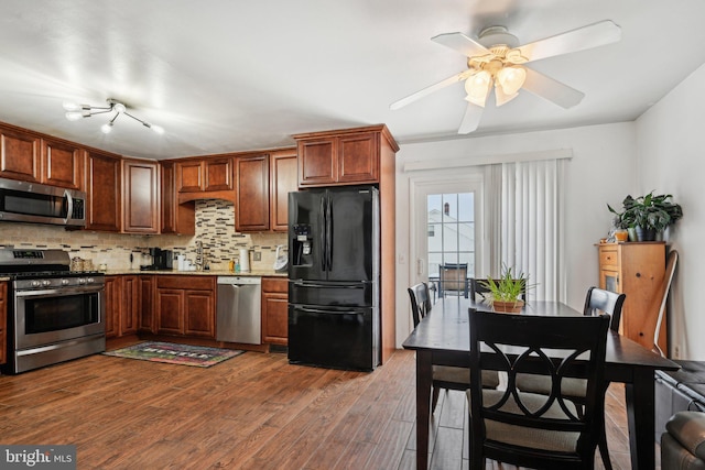 kitchen with appliances with stainless steel finishes, tasteful backsplash, sink, dark wood-type flooring, and ceiling fan