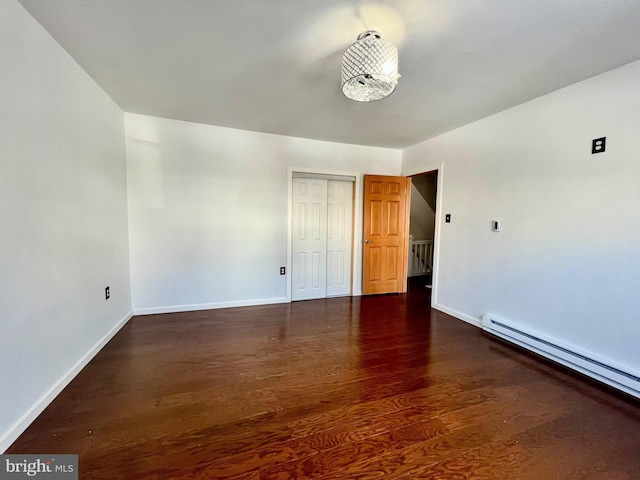 spare room with baseboard heating and dark hardwood / wood-style floors