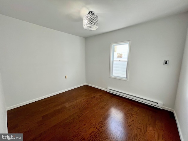 unfurnished room featuring baseboard heating and dark hardwood / wood-style floors