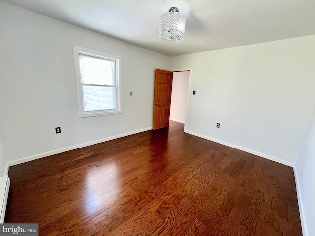 empty room featuring dark hardwood / wood-style floors and a baseboard radiator