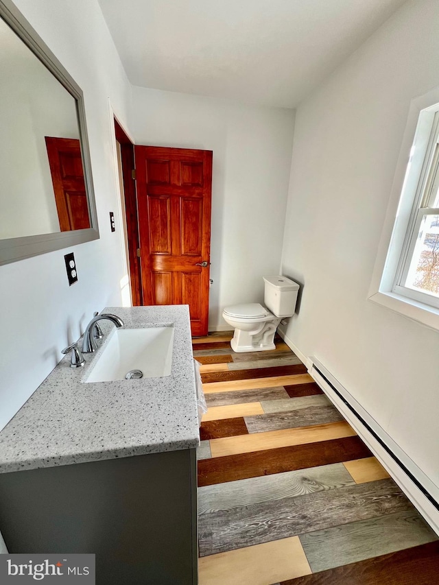 bathroom featuring a baseboard heating unit, toilet, hardwood / wood-style flooring, and vanity