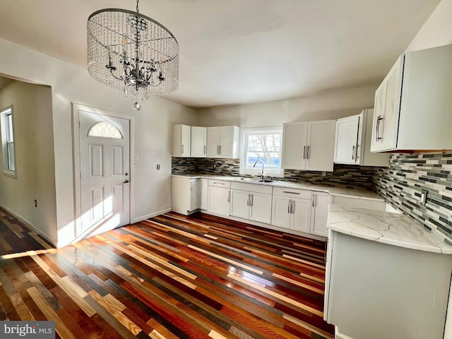 kitchen with white cabinetry, decorative light fixtures, light stone countertops, a chandelier, and sink