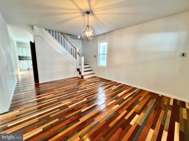 empty room with dark hardwood / wood-style flooring and a notable chandelier