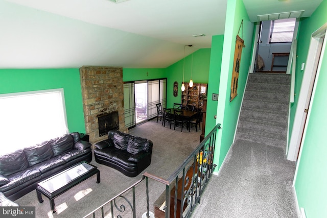 living room with dark colored carpet, vaulted ceiling, and a stone fireplace