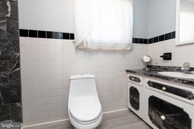 bathroom with plenty of natural light, toilet, vanity, and tile walls