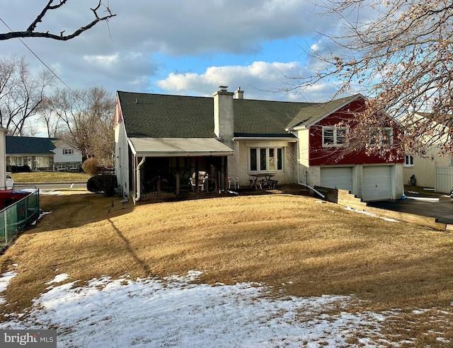 snow covered house featuring a garage and a yard