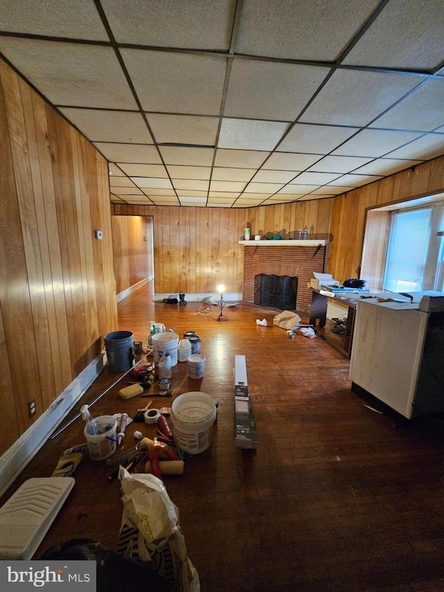 dining area with a brick fireplace, a paneled ceiling, and wooden walls