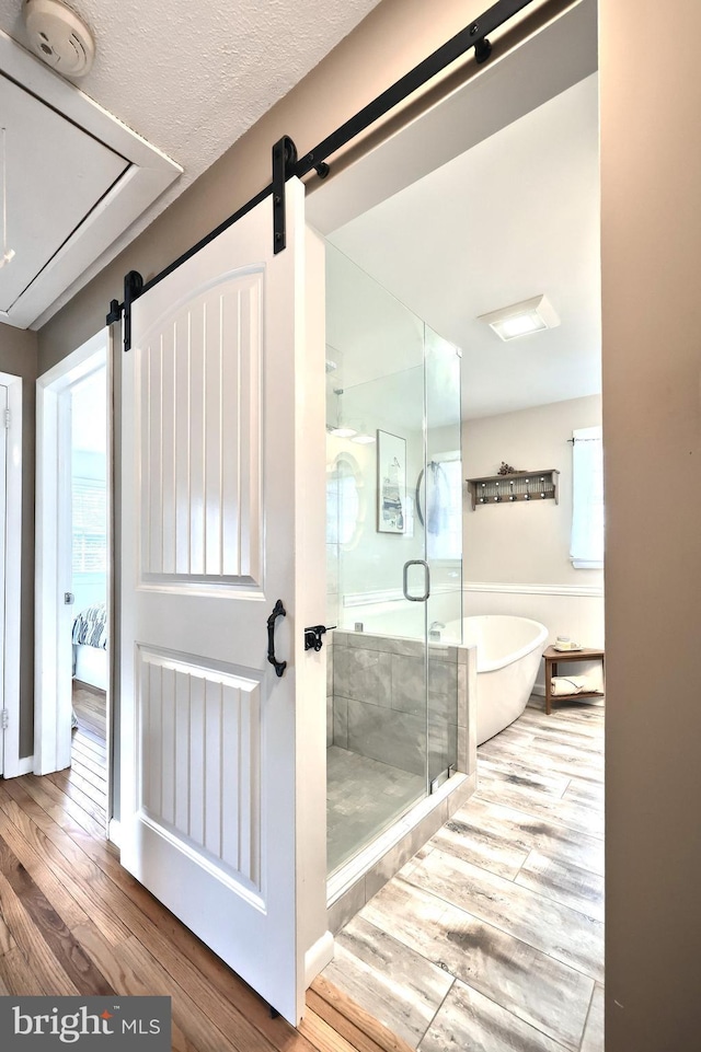 bathroom featuring a soaking tub, wood finished floors, a shower stall, and a textured ceiling