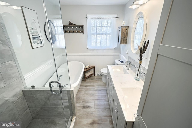 bathroom featuring a freestanding tub, wood finished floors, a shower stall, wainscoting, and vanity