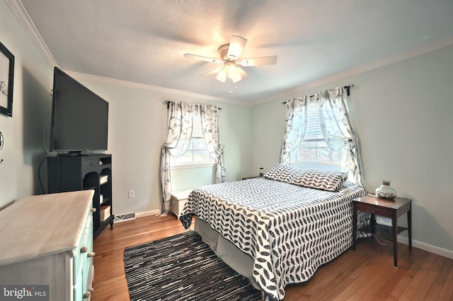 bedroom featuring wood finished floors, visible vents, and ornamental molding