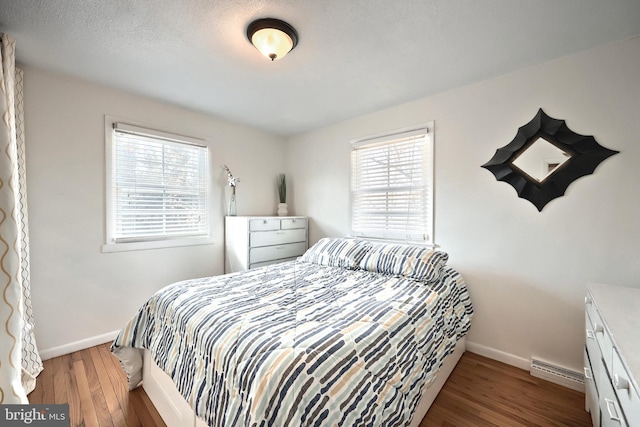 bedroom with multiple windows, baseboards, and wood finished floors