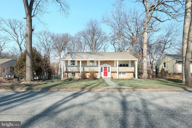 bi-level home with a chimney and a front lawn