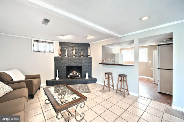 living area featuring light tile patterned floors, visible vents, a fireplace, and crown molding