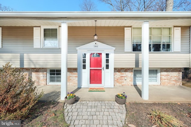 entrance to property featuring covered porch and brick siding