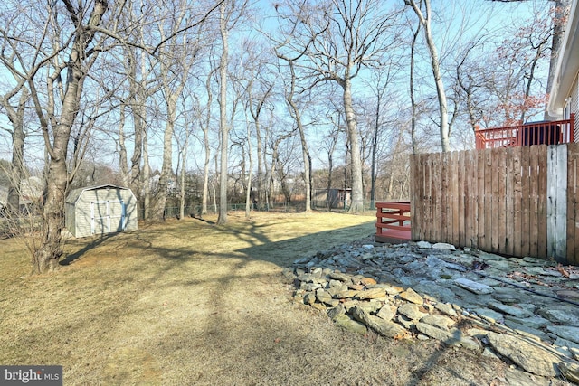 view of yard with fence, an outbuilding, and a shed