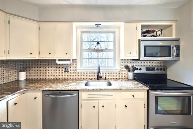 kitchen featuring a sink, light stone counters, a textured ceiling, appliances with stainless steel finishes, and decorative backsplash