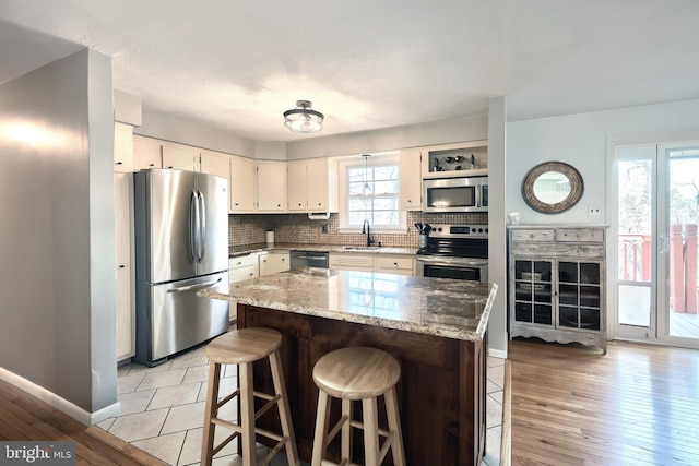 kitchen with backsplash, a breakfast bar area, light wood-style flooring, appliances with stainless steel finishes, and a sink