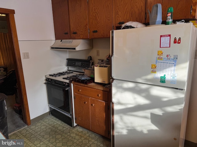 kitchen featuring range hood, white refrigerator, and range with gas cooktop