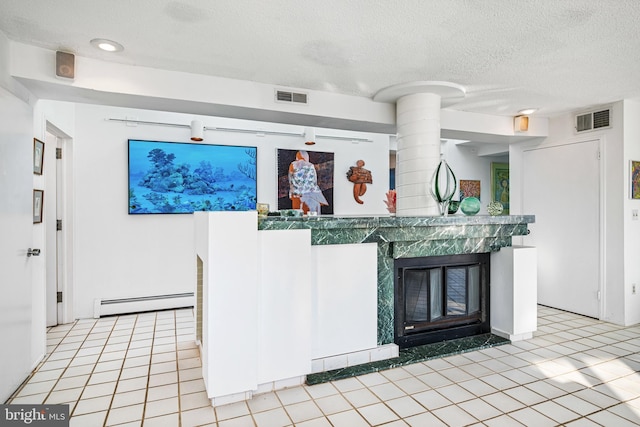 kitchen featuring light tile patterned floors, a textured ceiling, and baseboard heating