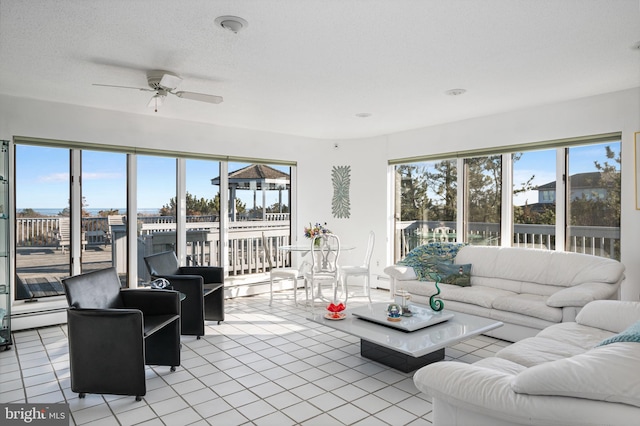 tiled living room with ceiling fan, a baseboard heating unit, and a textured ceiling